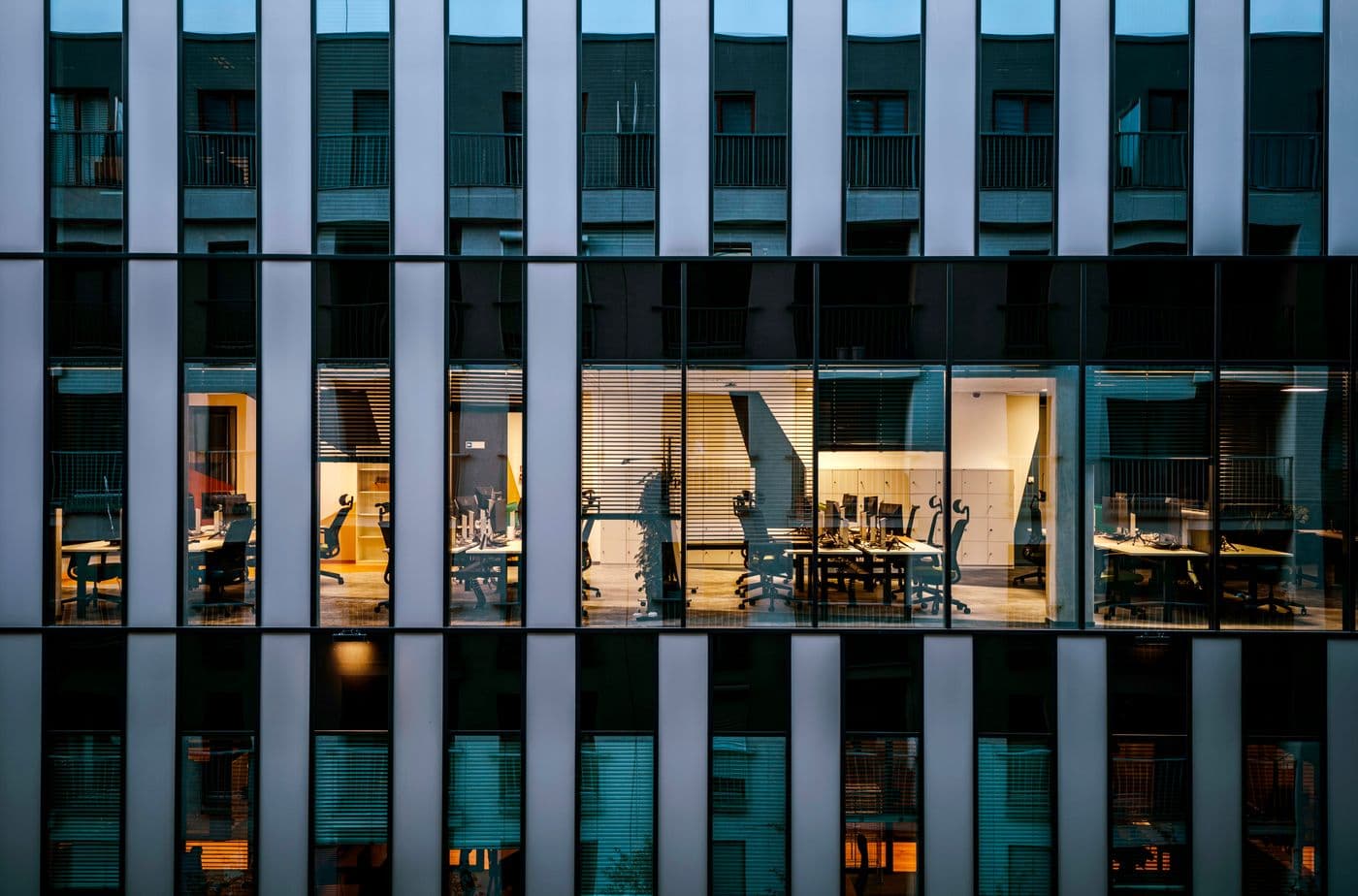 Modern glass-fronted commercial building lit from inside on a city street