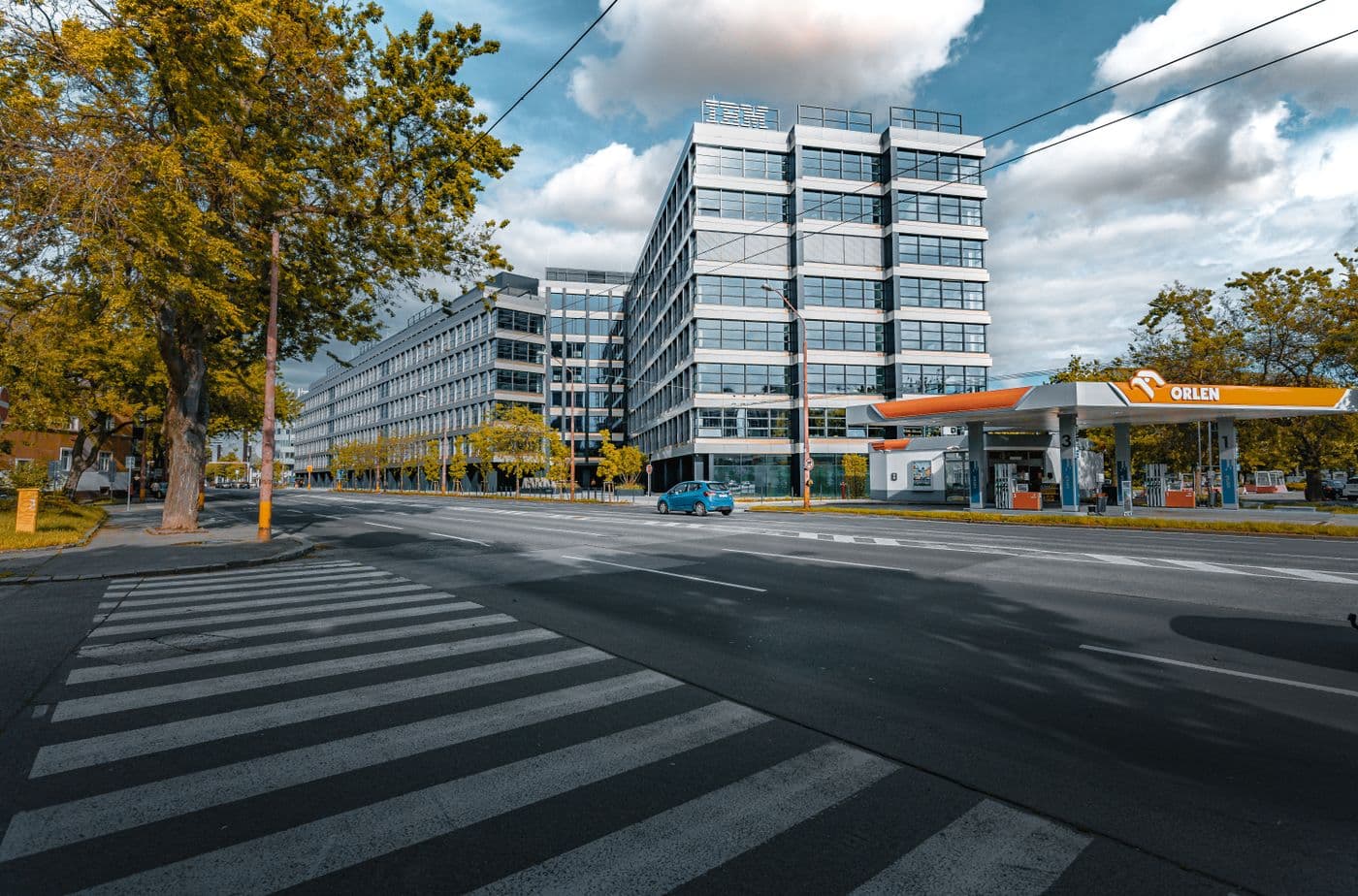 Modern office building beside a tree-lined road at a city junction