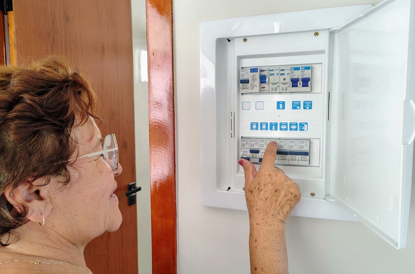 Person operating a wall-mounted electrical control panel at home