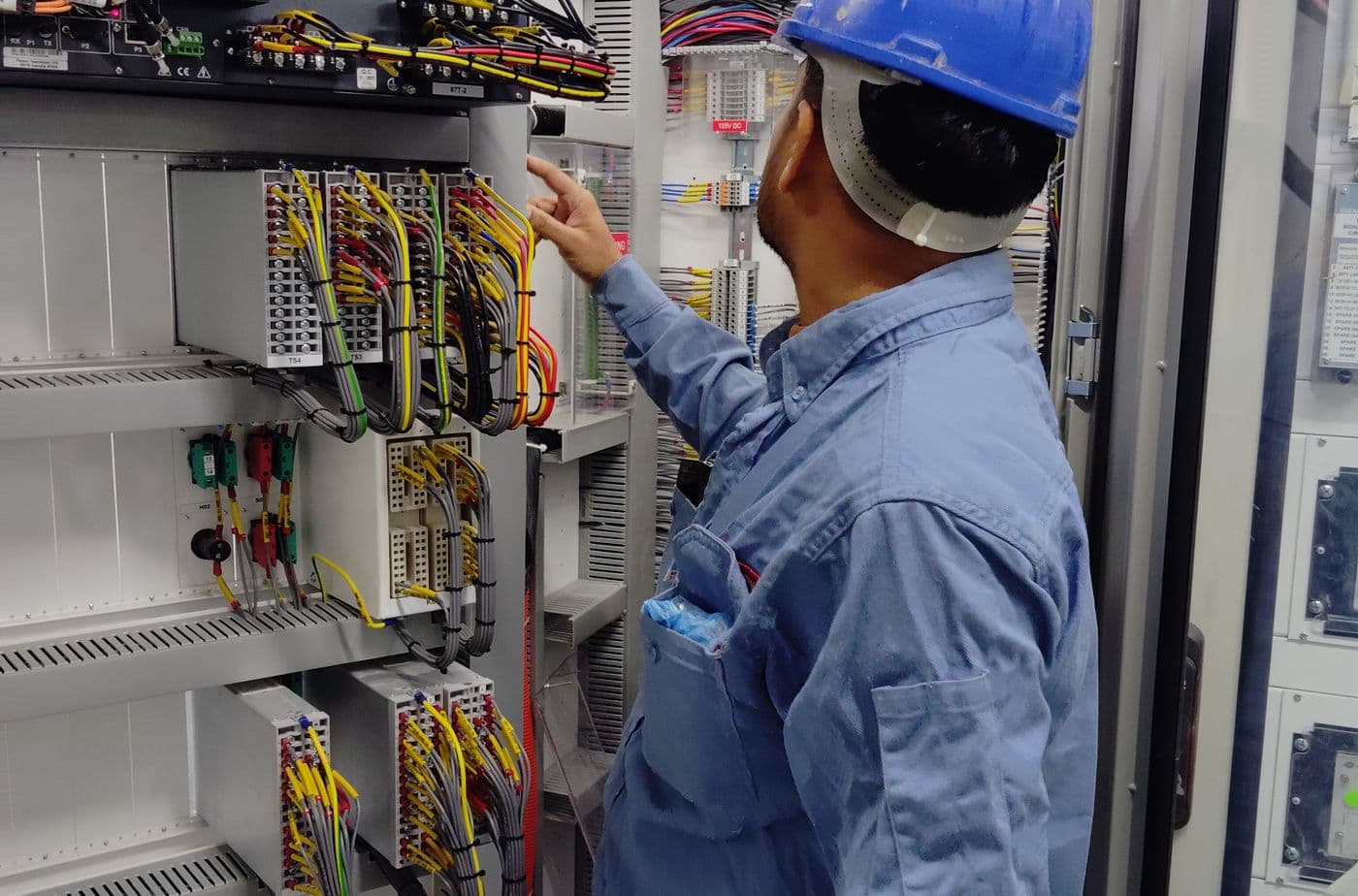 Electrician in uniform checking cabling during a routine maintenance visit