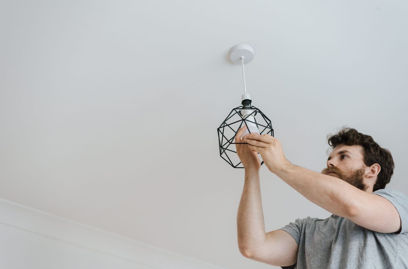 Electrician fitting a ceiling light in a freshly finished room